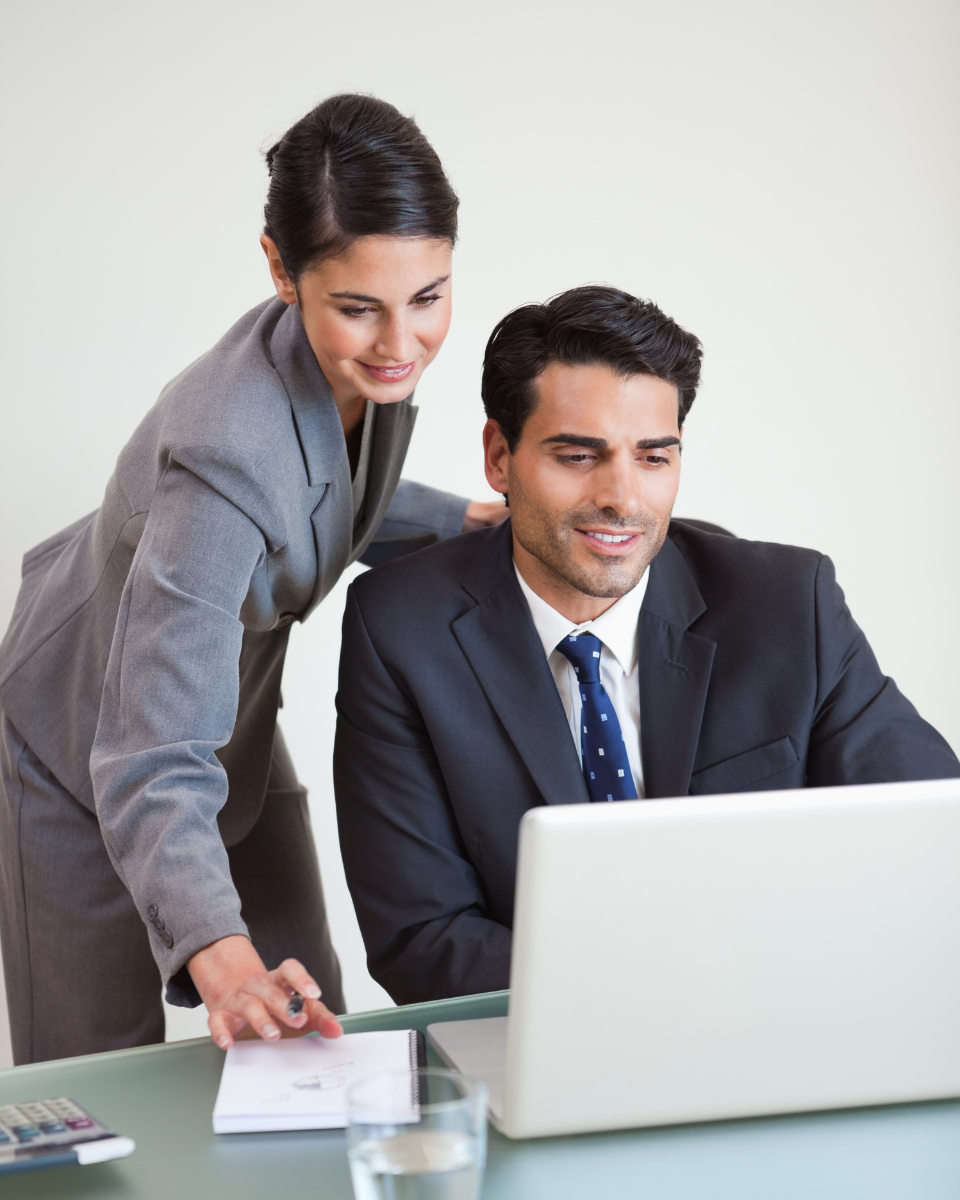 Homem e mulher sorrindo em frente ao computador.