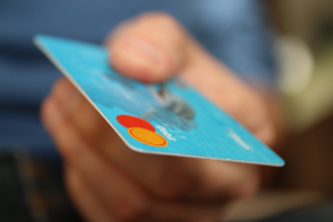 Mão segurando um cartão de crédito, simbolizando um pagamento de algum produto no dia das crianças.
